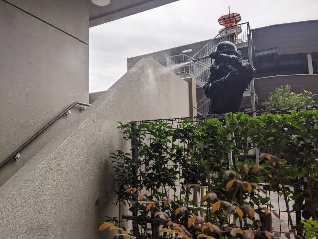 ビルの外壁に高圧洗浄をかける作業員